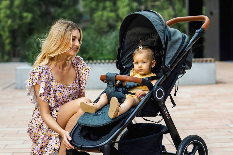 Mama kuca przy córce obok wózka spacerowego – zdjęcie do bloga o tym, od kiedy wybrać spacerówkę